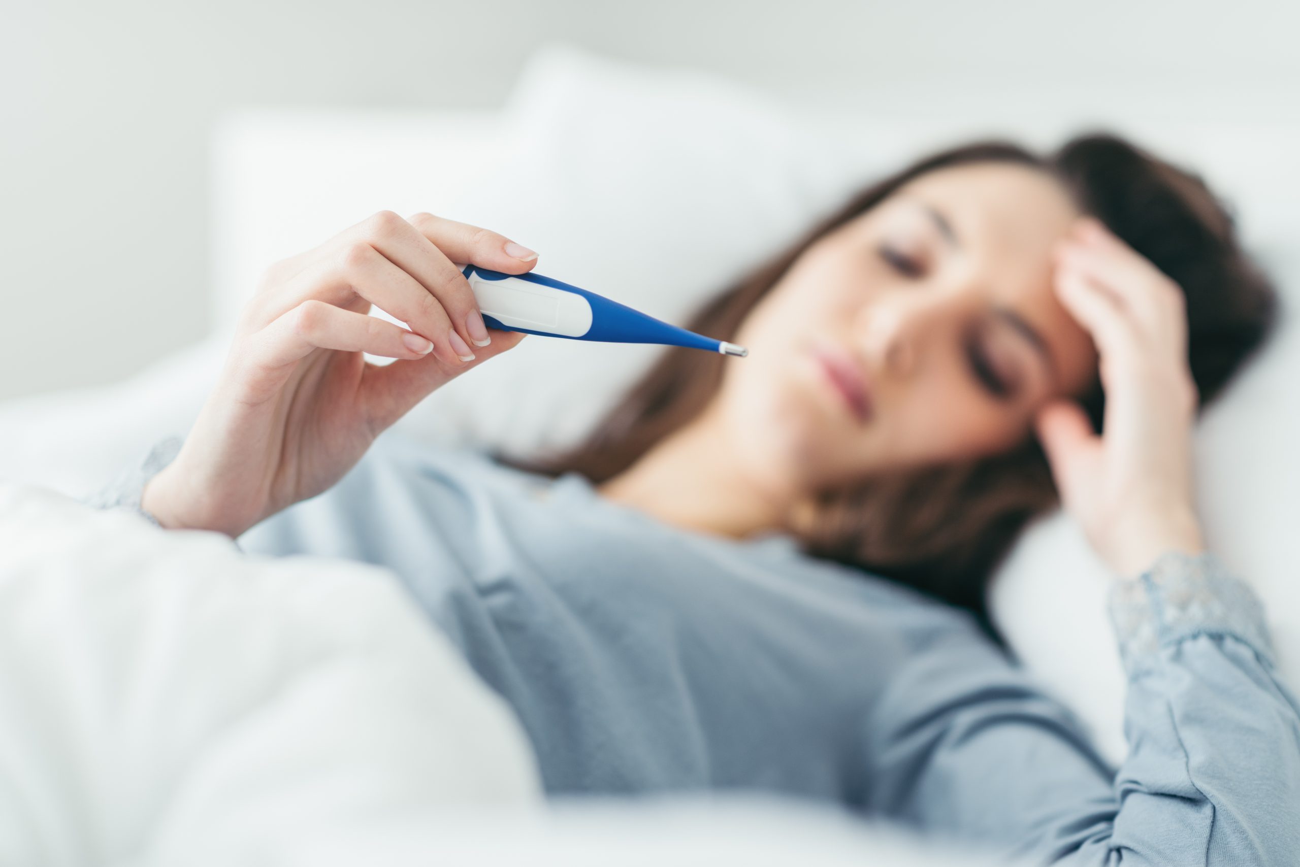 Woman lying in bed reading a thermometer