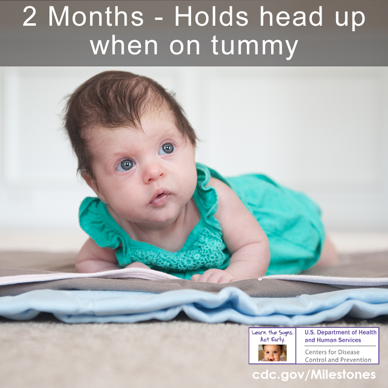 The baby in this photo is holding her head up as she lays on her tummy, a 2-month movement/physical development milestone.