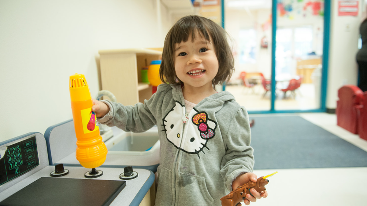 Una ni&ntilde;a de 2 a&ntilde;os juega en una cocinita de juguete.