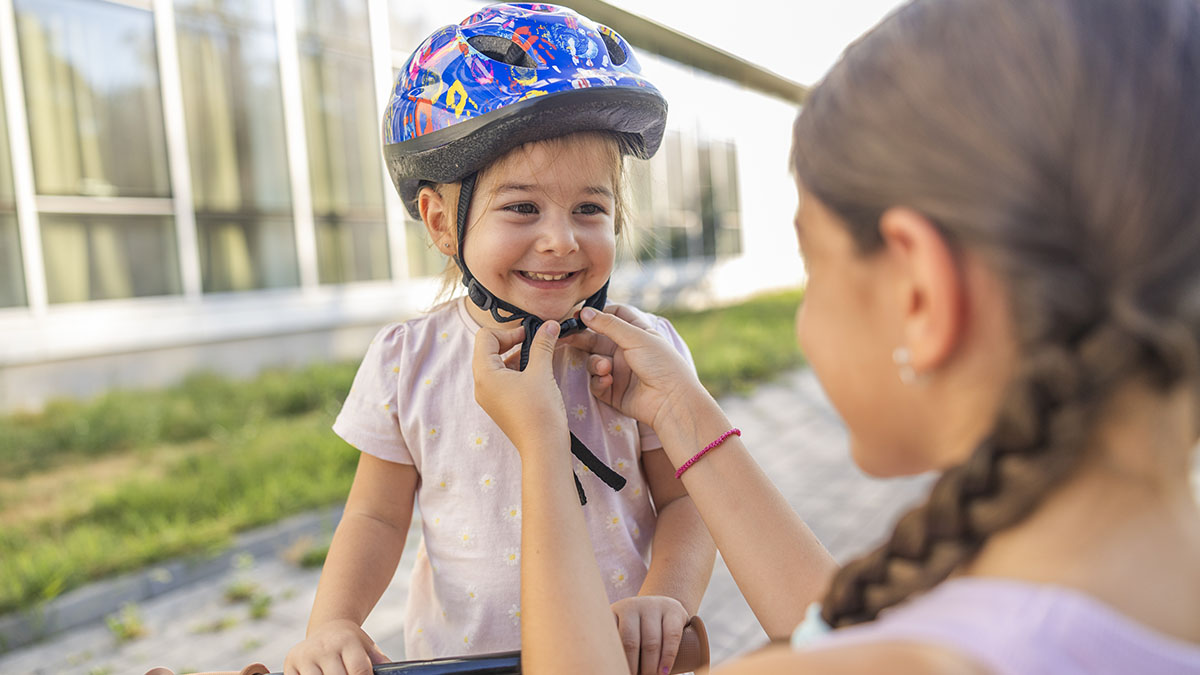 Family member adjusting the helmet on a young child.