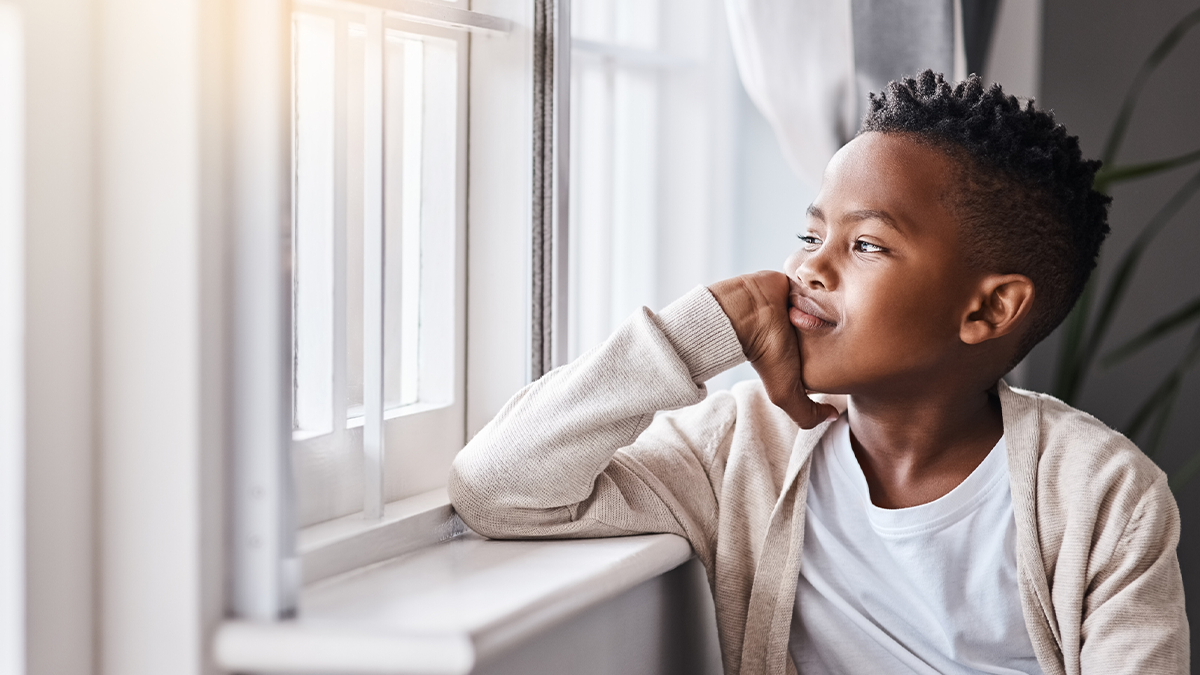A child sits pensively looking out of the window.