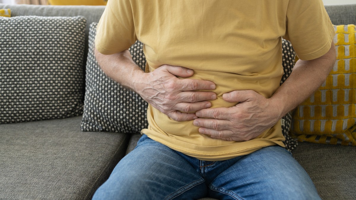 Un hombre se lleva las manos al estómago, lo que indica síntomas de dolor.