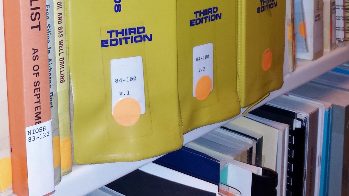 Two library shelves are filled with a number of medical publications.