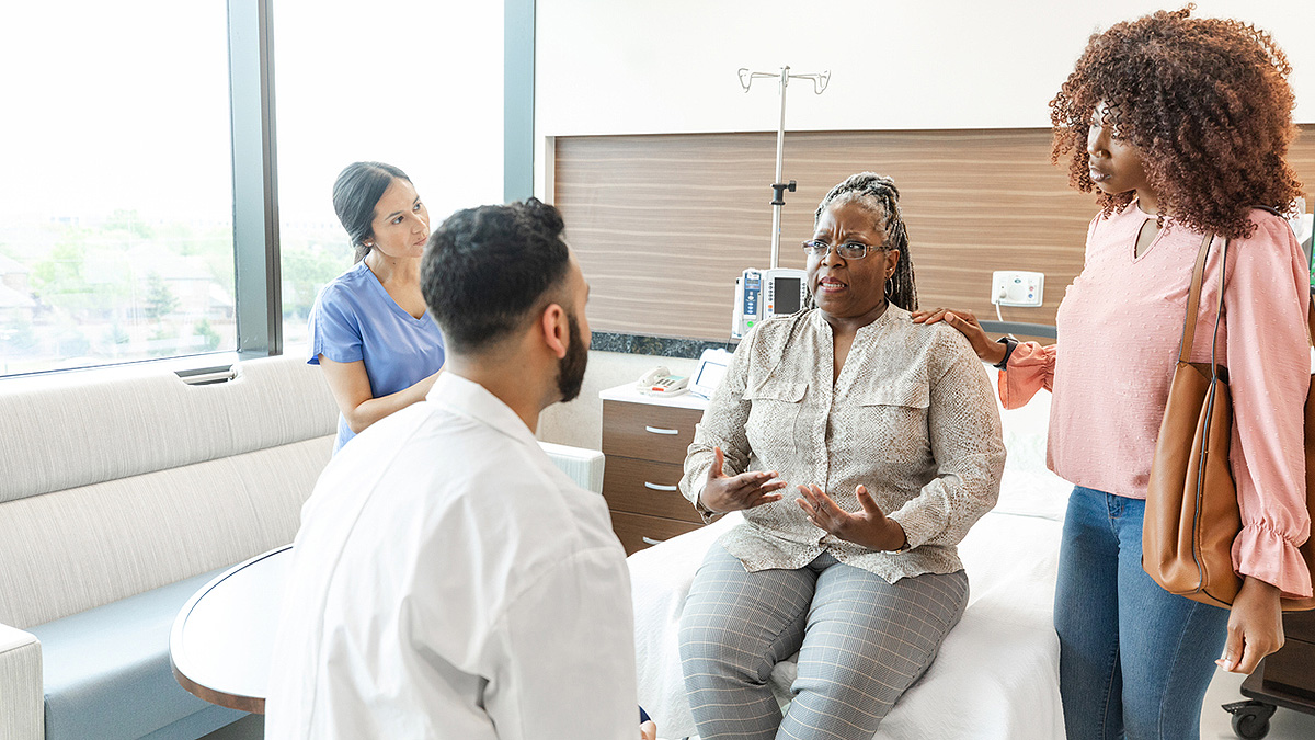 Serious woman and daughter talk to male doctor Woman talking with doctor with family present