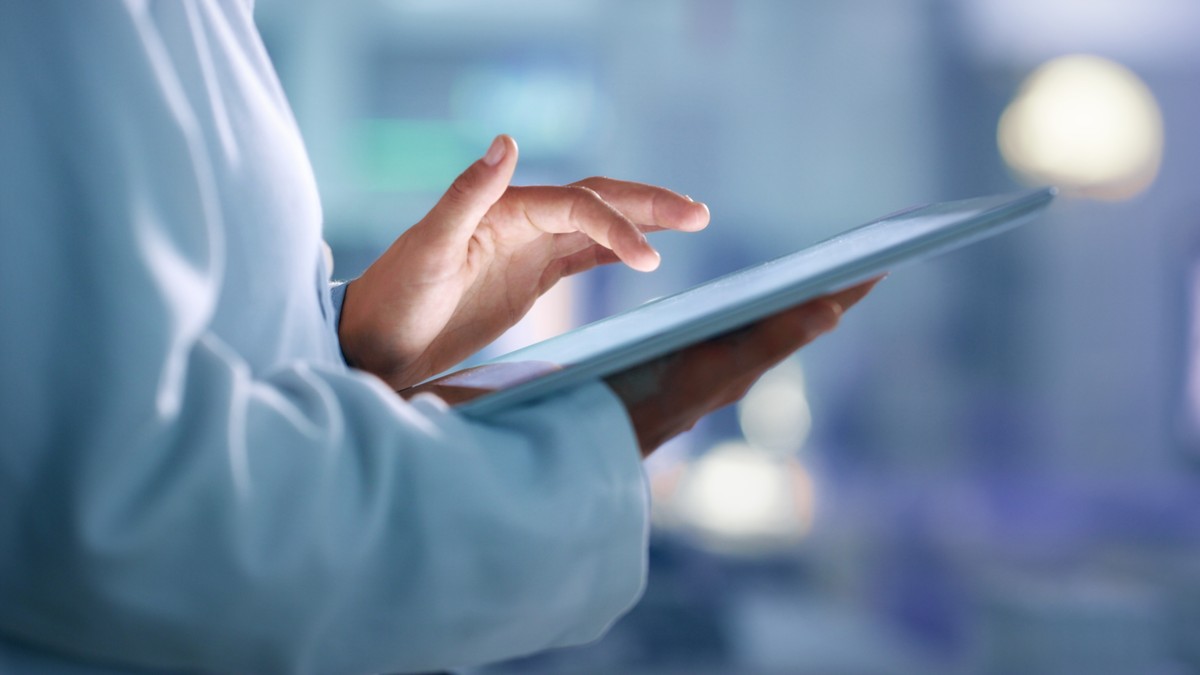 A healthcare provider uses a tablet to enter patient information.