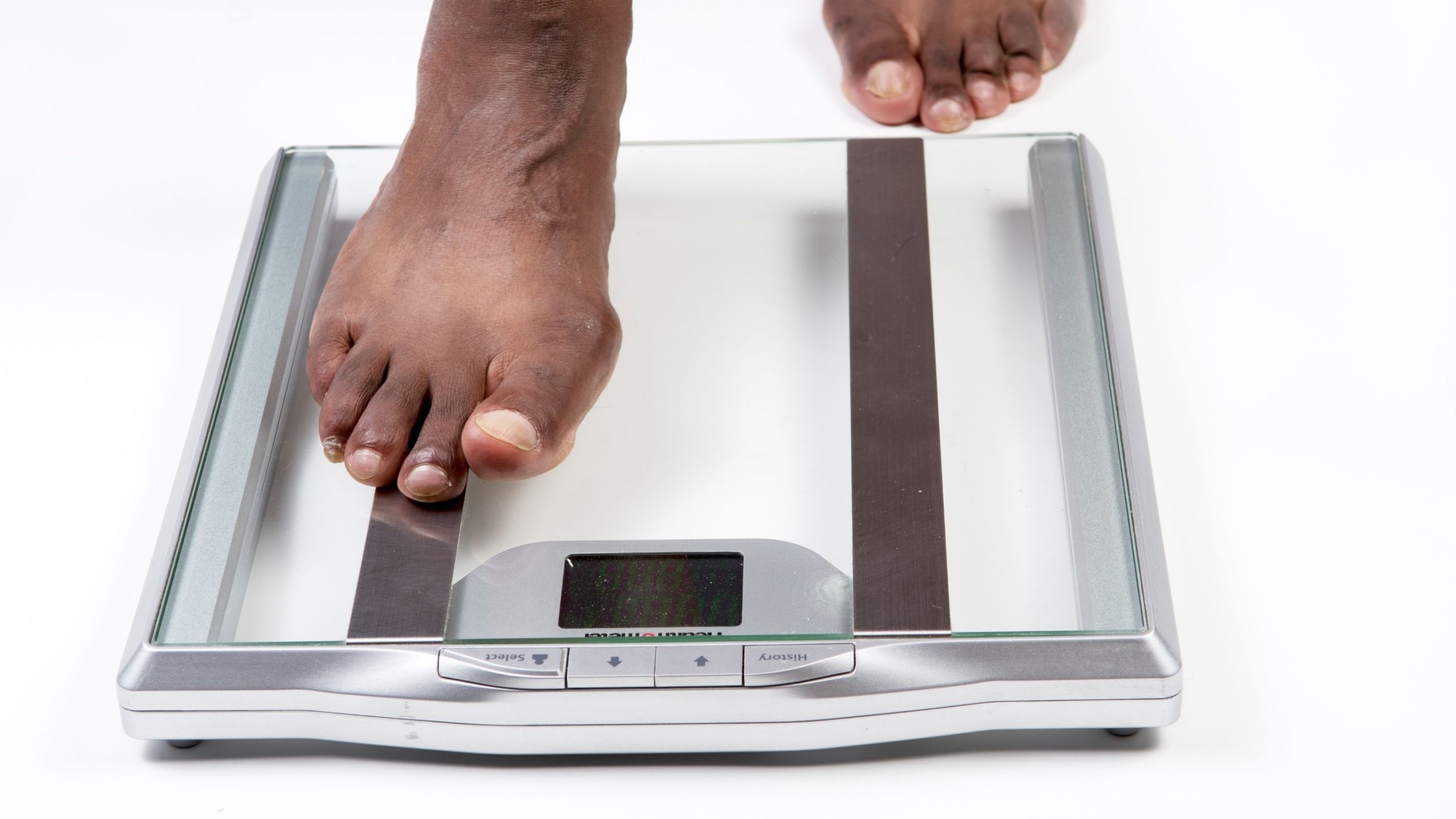 male feet stepping on electronic scales A person's feet stepping on electronic scales.