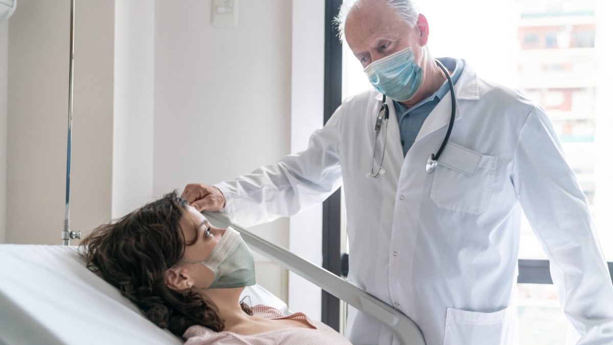a breast cancer patient in a hospital bed talking to her doctor