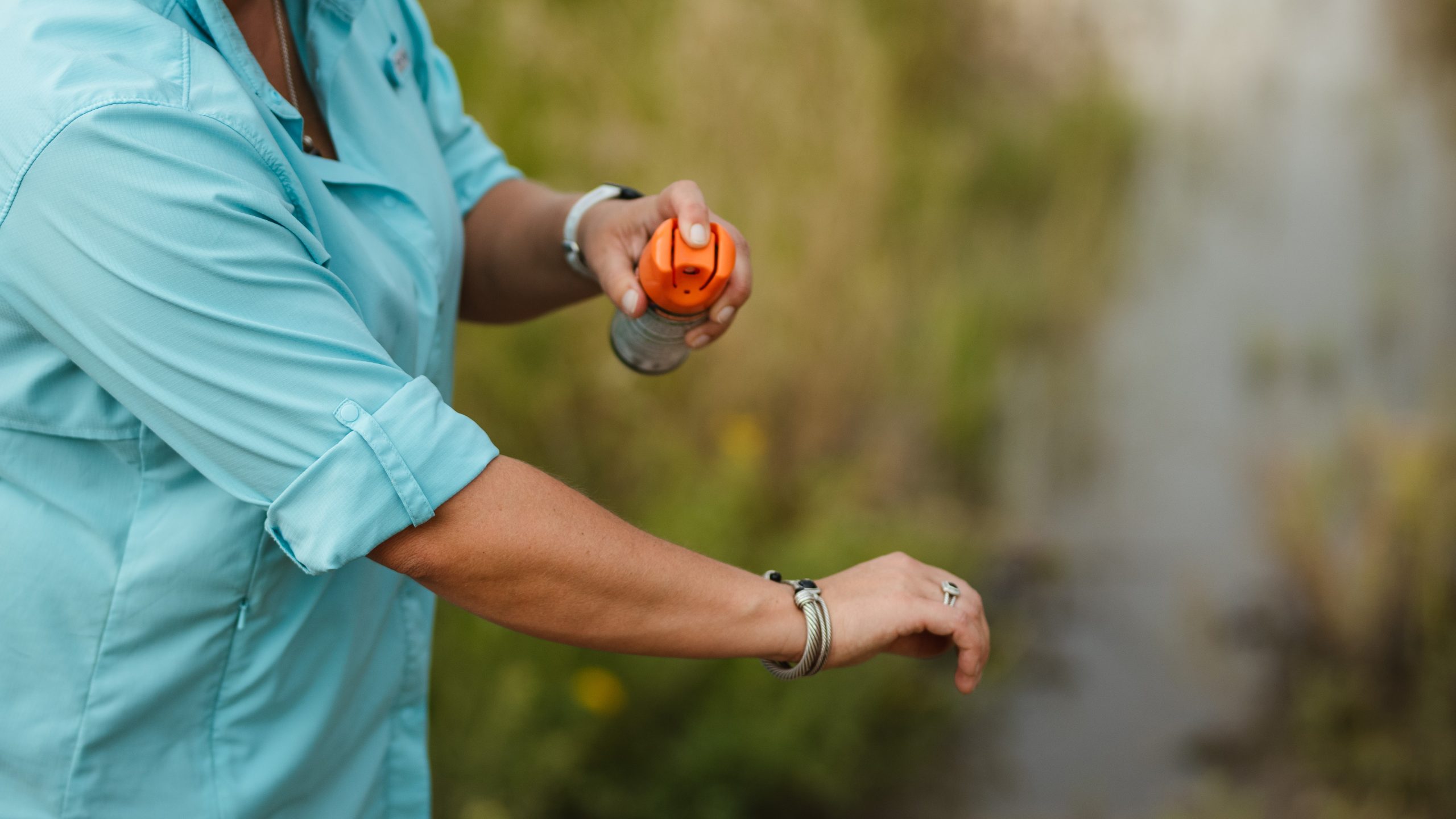 Spraying mosquito repellent on arm.