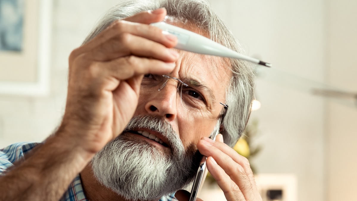 Man thermometer a man looking at a thermometer and calling his doctor