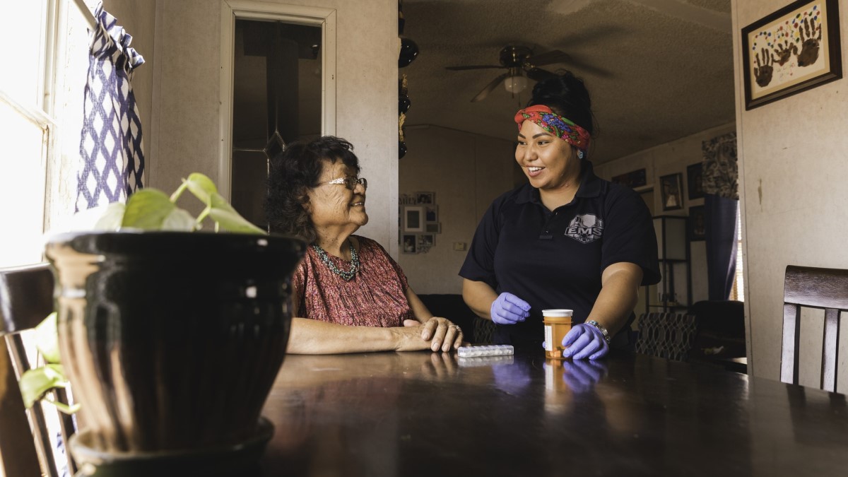 A community health worker helps a woman with her medication