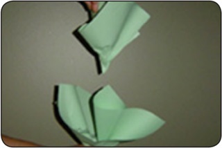 A person folds sheets of green paper to form a paper cabbage