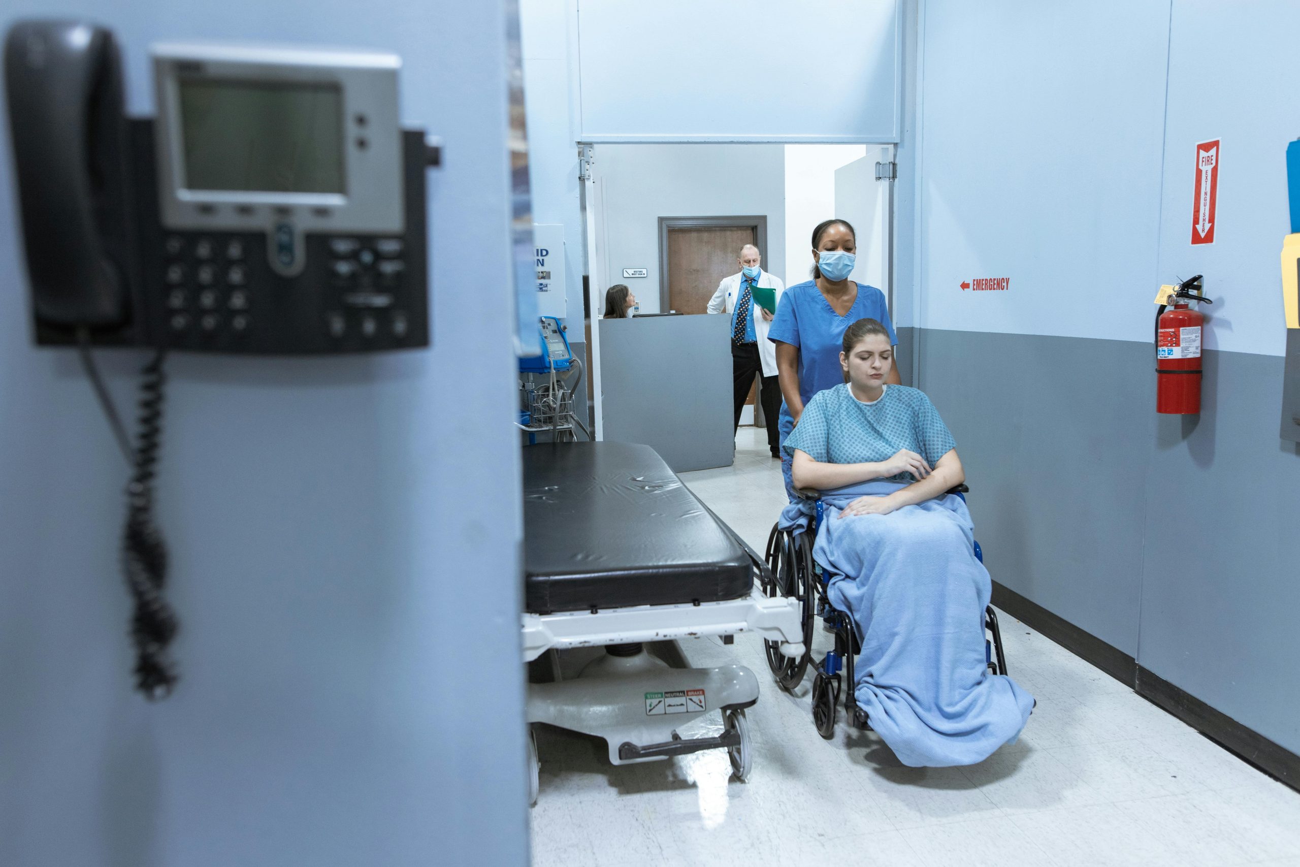 healthcare staff & patient Healthcare personnel pushing patient in wheelchair.
