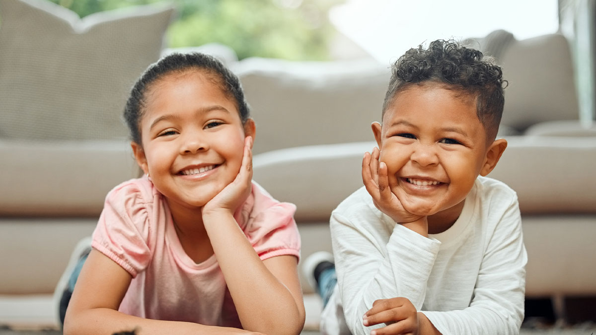 Brother and sister laying on ground smiling