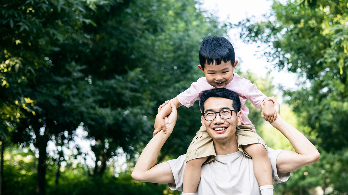 Son on his father's shoulders with trees around