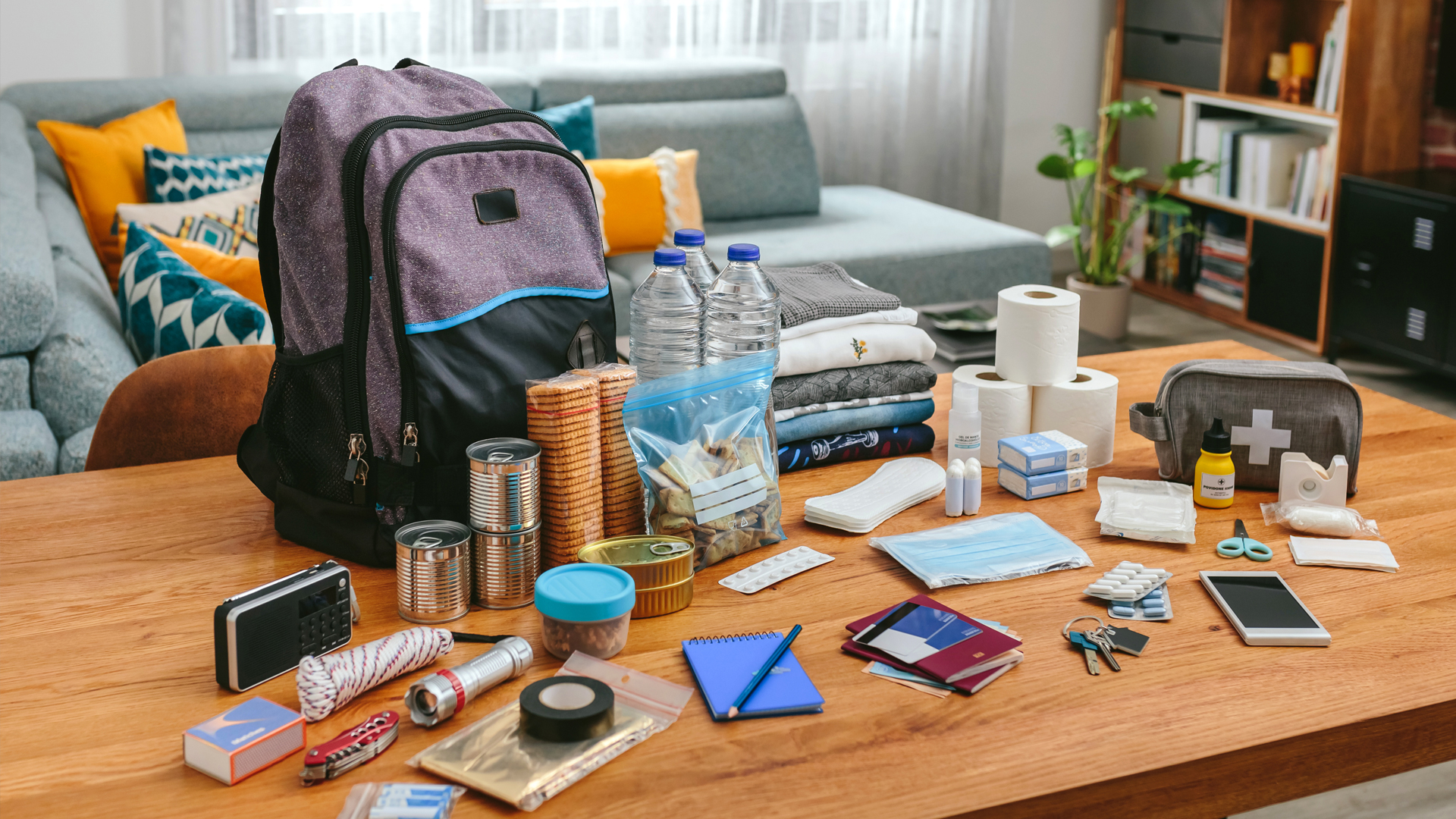 backpack on a coffee table being packed with items useful for pregnant people to plan for emergencies