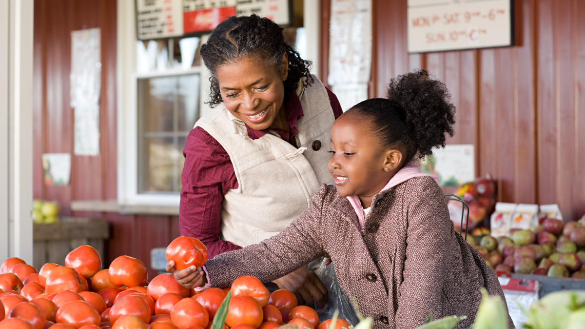 Madre e hija eligiendo verduras en un mercado de agricultoras