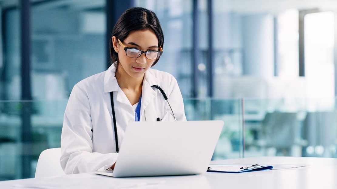 Clinician on laptop computer conducting research.