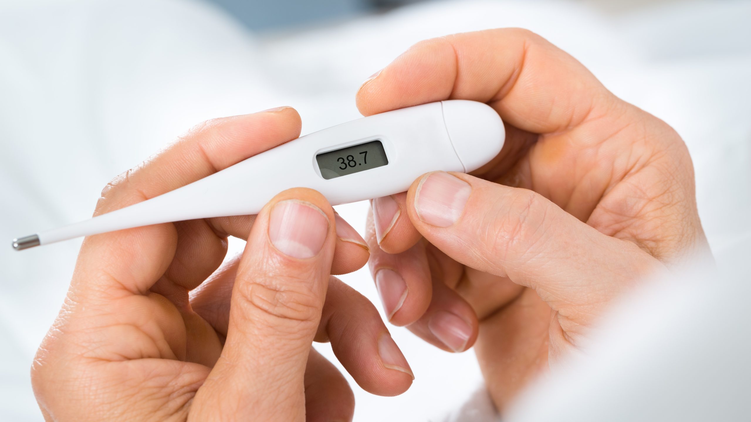 A patient reads a digital thermometer.