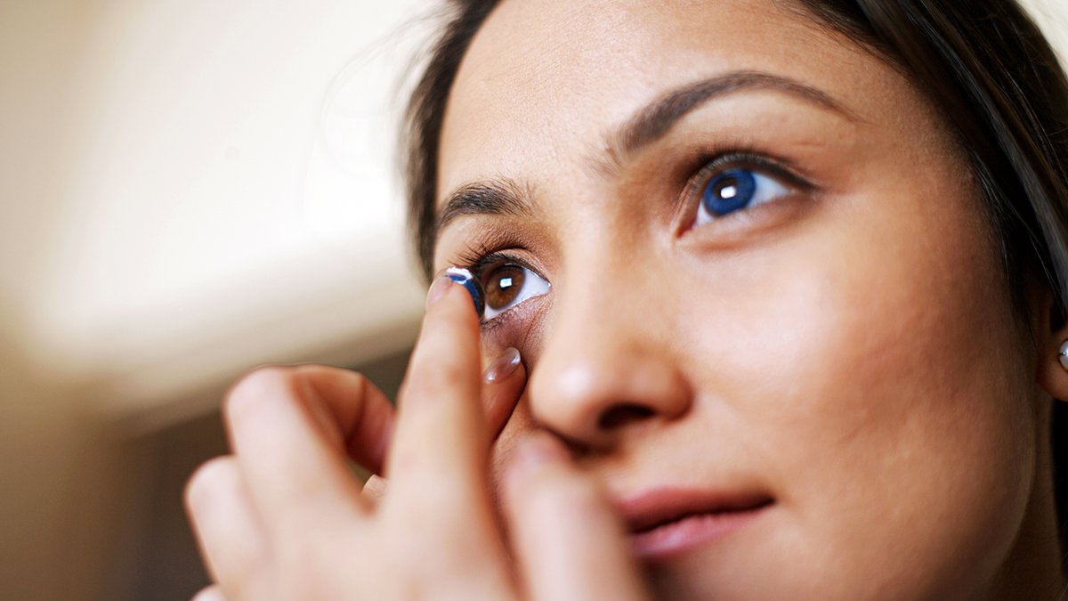 Woman putting on colored contact lenses