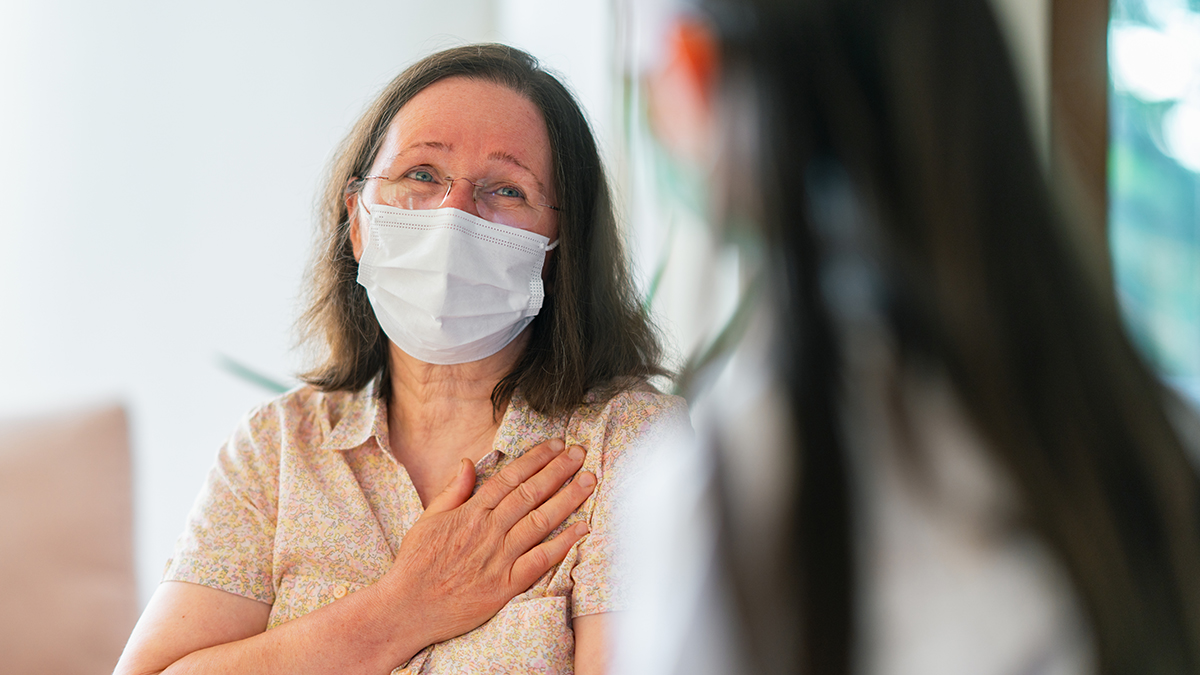 Female patient with mask talking with doctor.