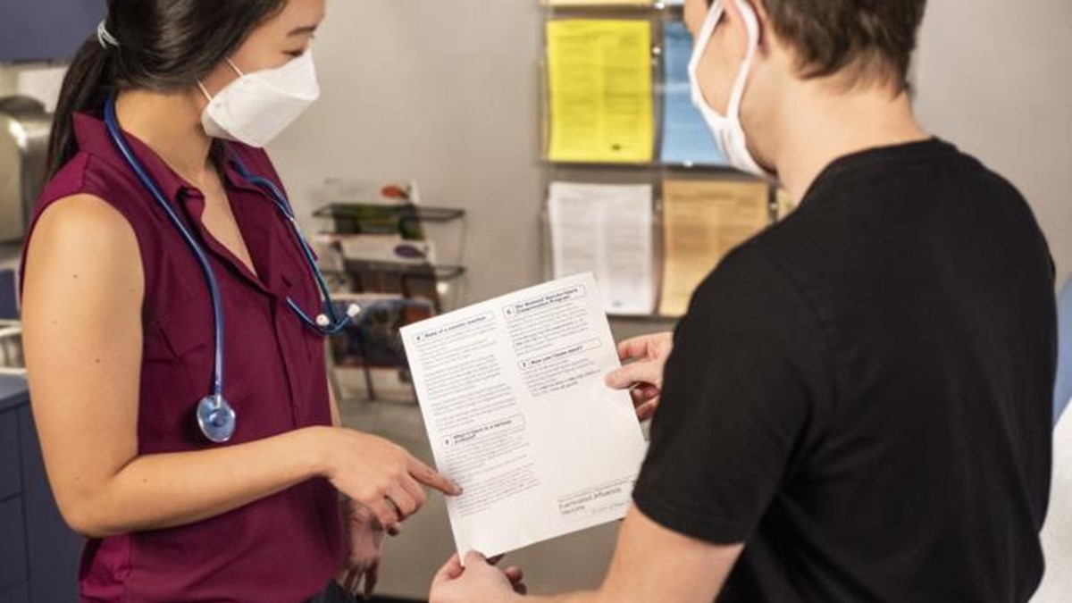 Proveedor de atención médica revisa el material educativo con un paciente en una sala de examen.