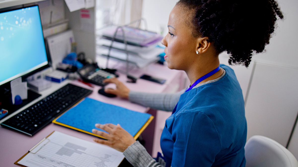 A female HCP works on a computer in an office