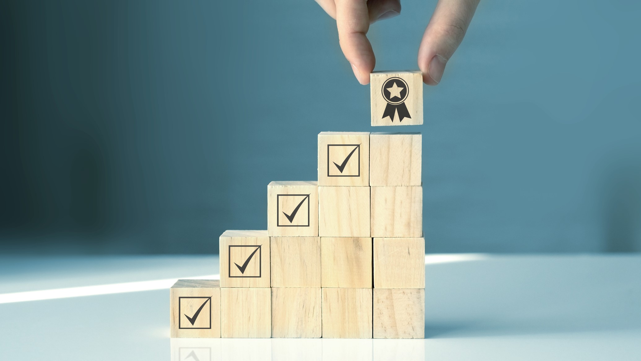 Stacked wooden blocks with check marks and a medal block on top