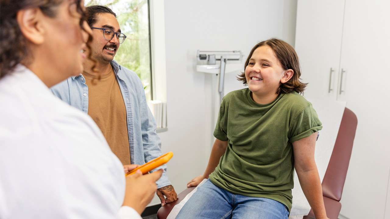 Health care provider talking with parent and preteen child.