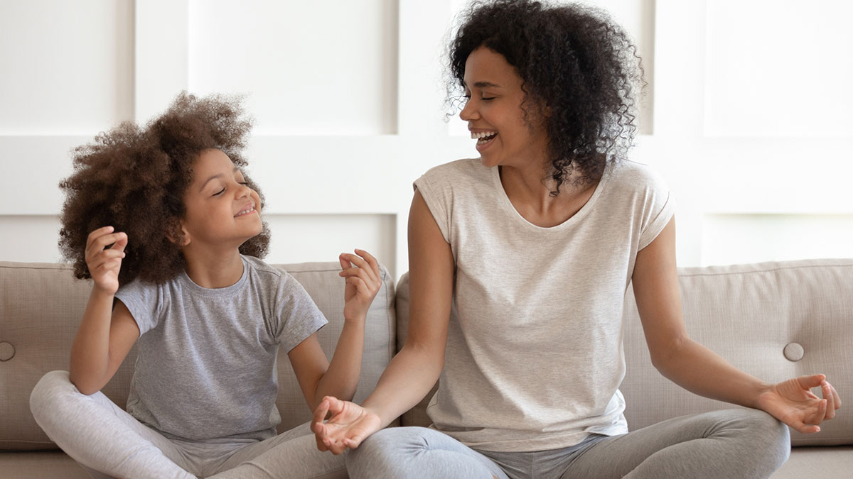 African American woman teaching young daughter meditation and yoga exercises