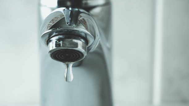 Llave de agua con una gota de agua saliendo.