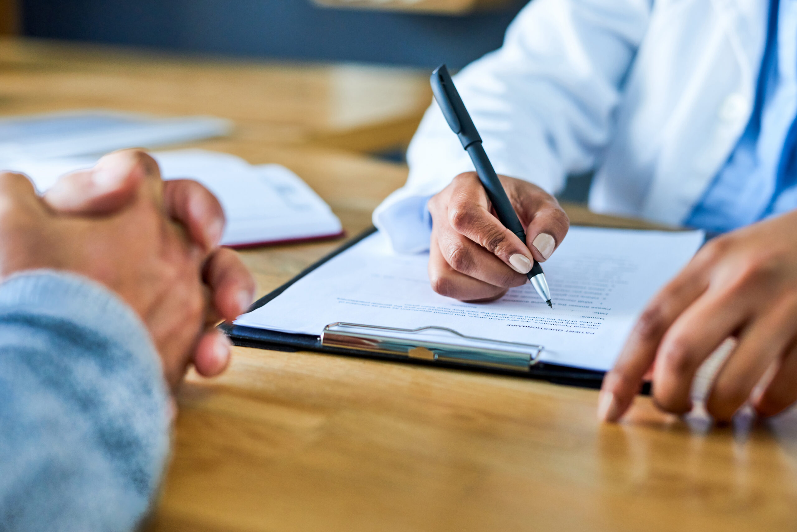 A professional writes on a clipboard at a desk.