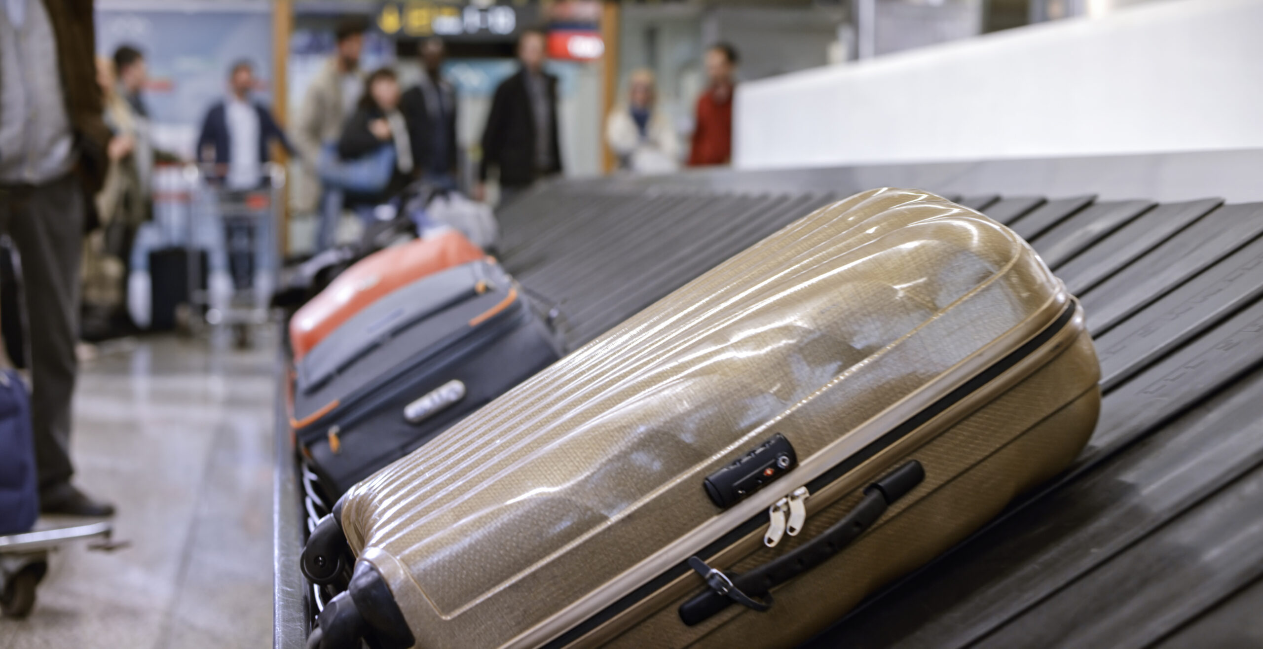 Different suitcases sit on a luggage carousel in an airport.