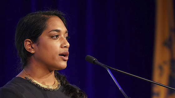 Female EIS officer standing on stage in front of microphone.