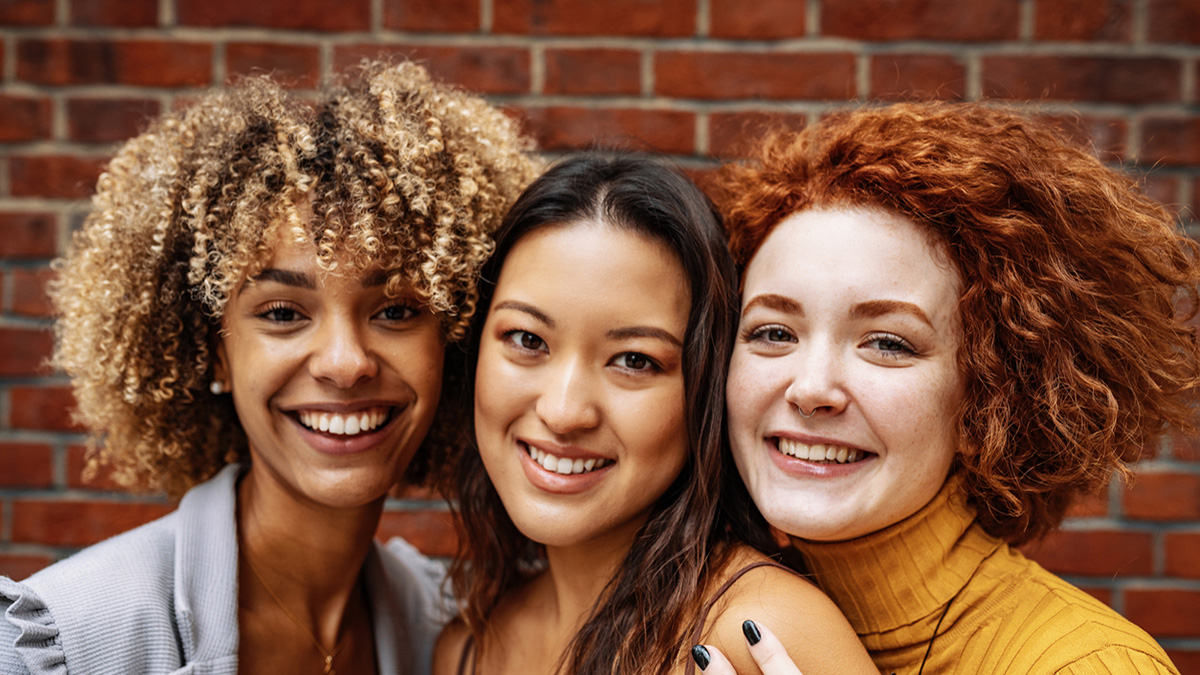 Three women standing closely together and smiling. Three women standing closely together and smiling