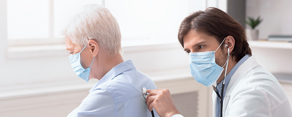 Doctor using stethoscope on person's back.