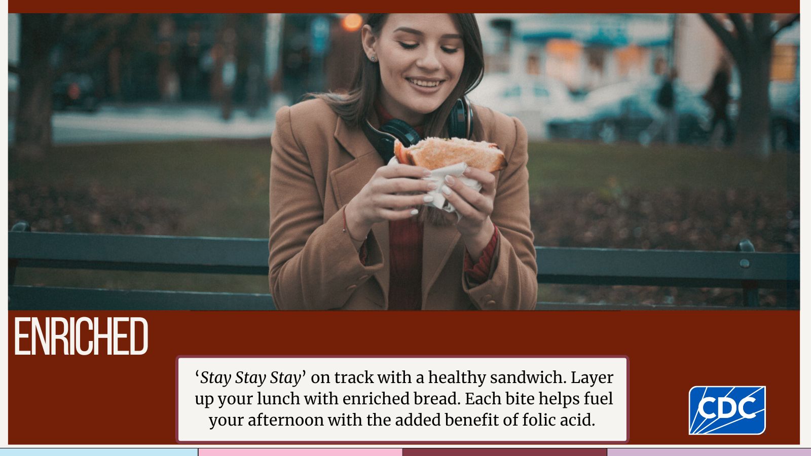 Young adult sitting outside eating a sandwich.