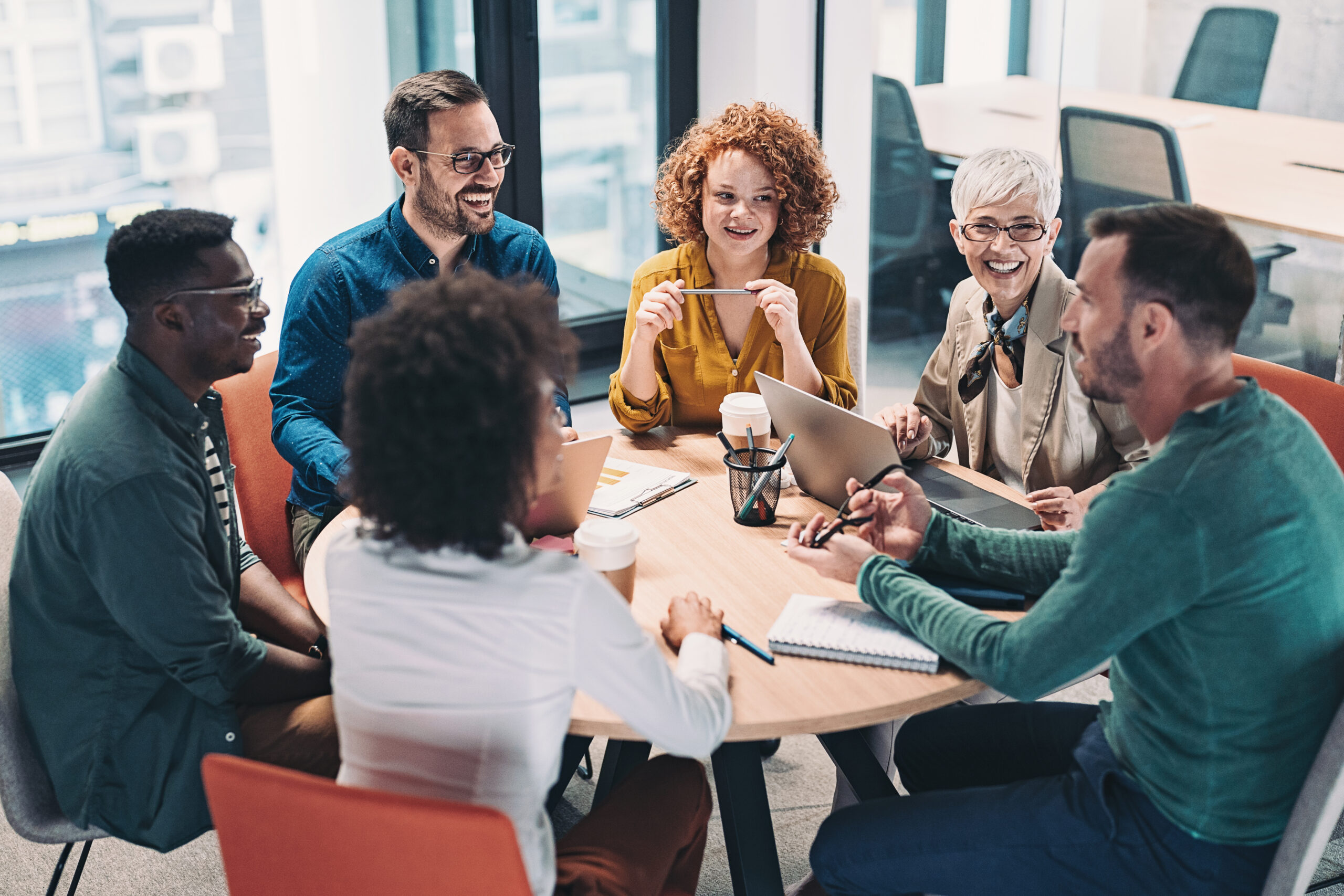 Six colleagues sitting around a table during a meeting