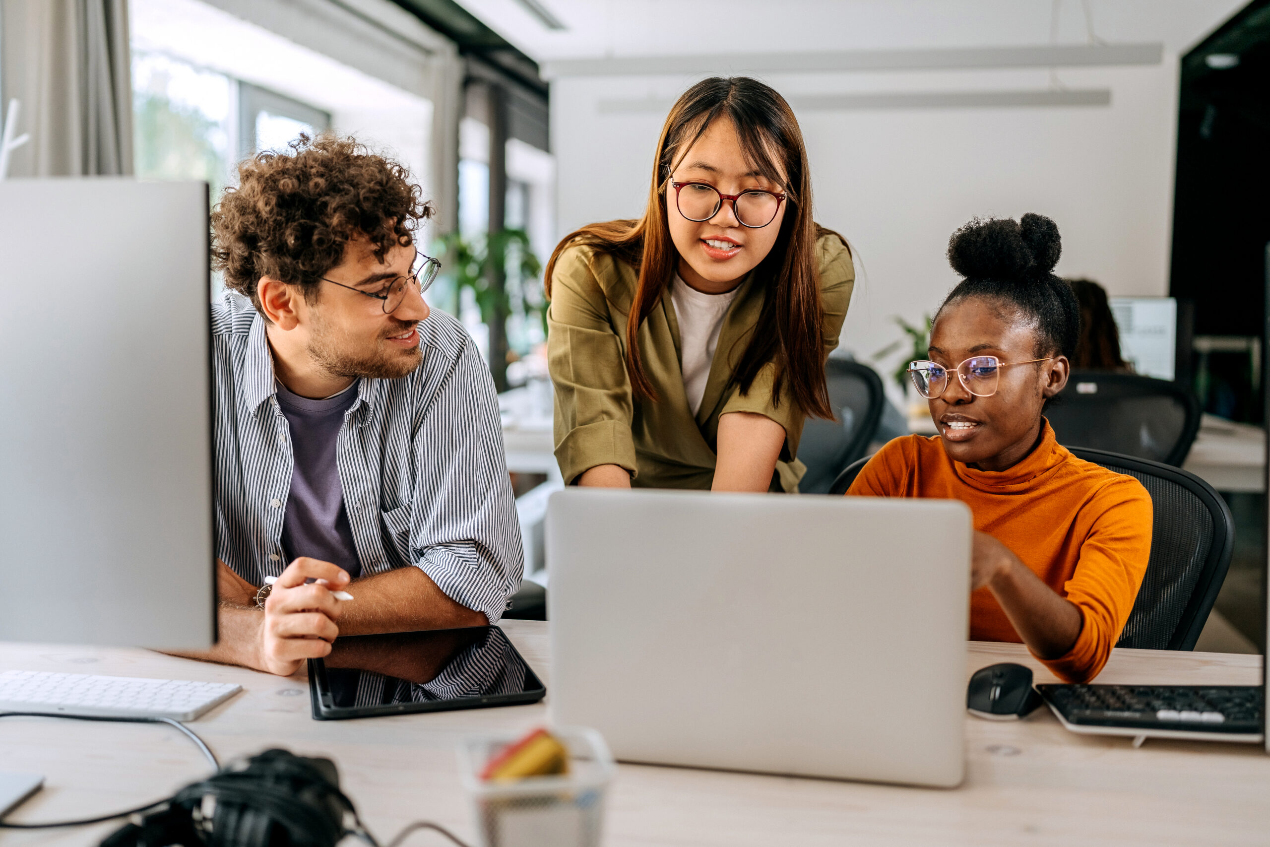Three college- or graduate-level students looking at a laptop together