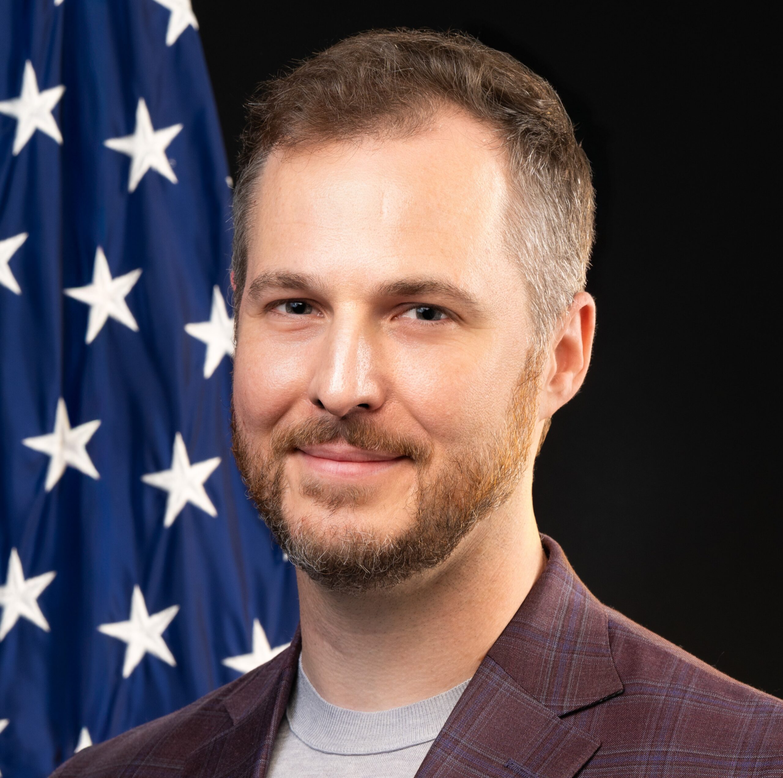 Dr. Asher is the director of the Center for Forecasting and Outbreak Analytics, has short brown hair and is wearing a plaid suit jacket.