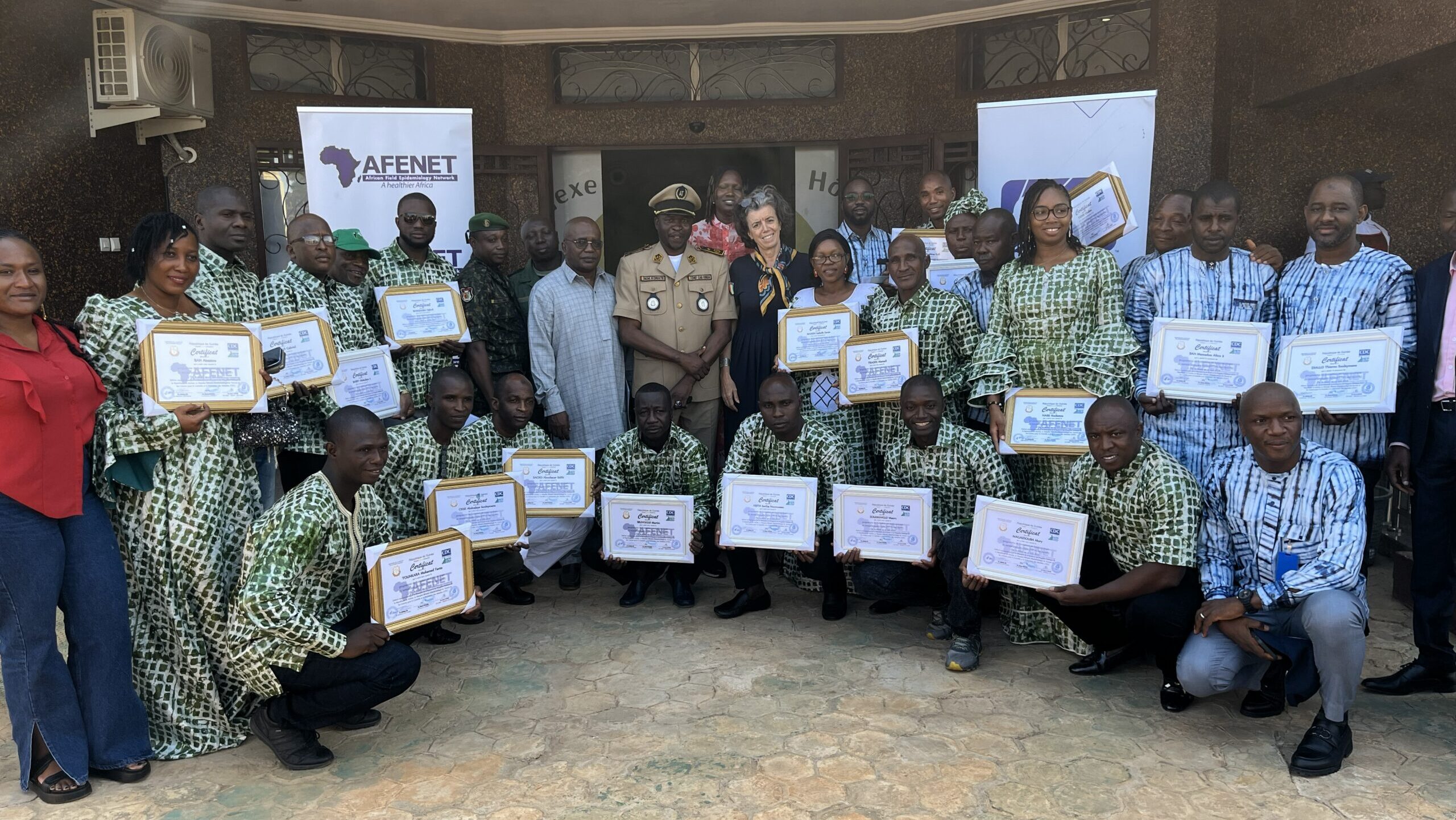 Photo of a large group holding diplomas at FETP graduation in Guinea