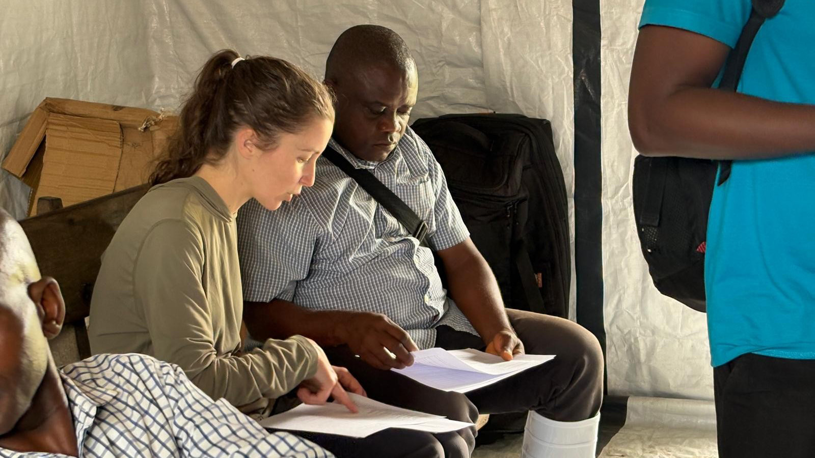 Two people sitting down, looking at papers.