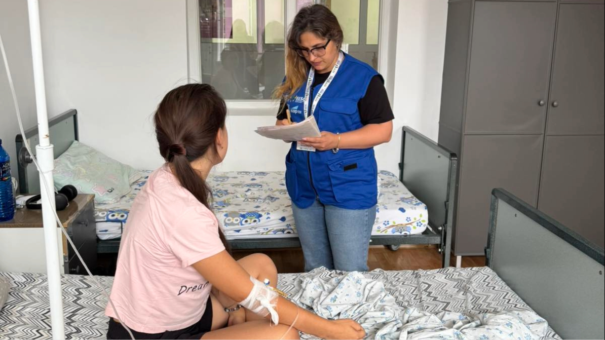 A woman interviews a patient in a healthcare setting.
