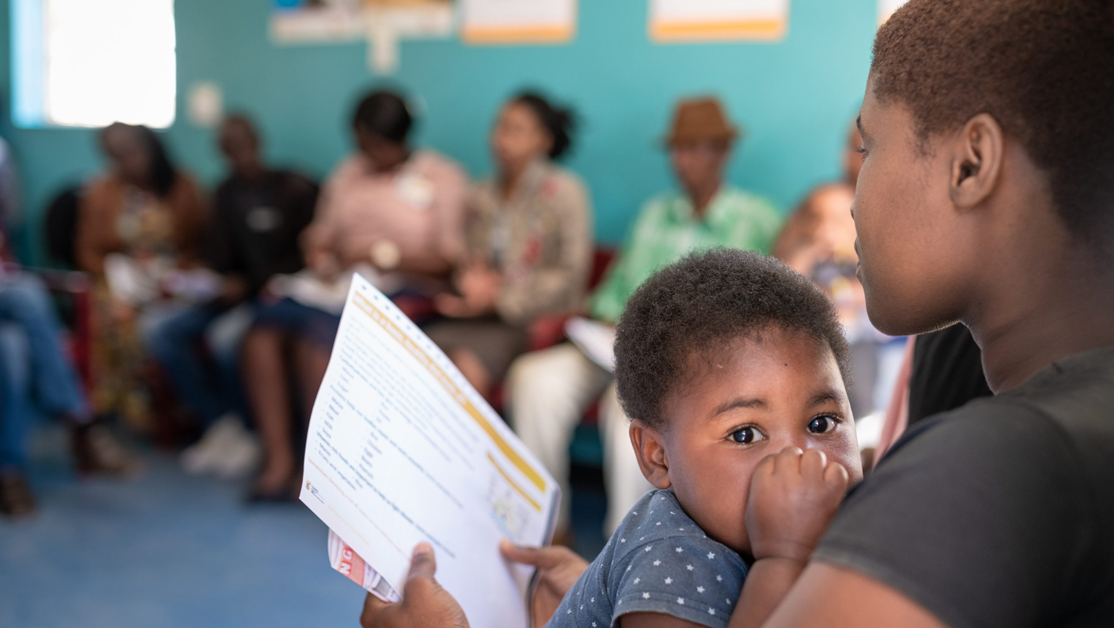 Image of mother holding baby and a piece of paper in office setting