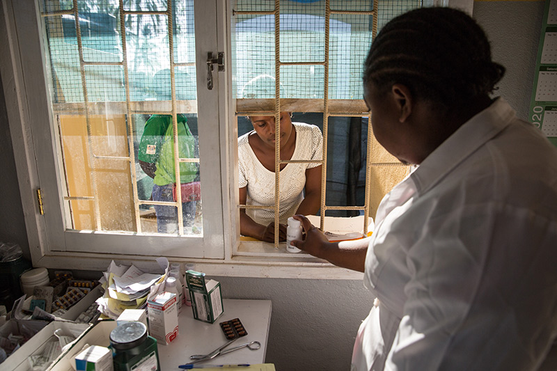 Woman handling medication to another woman at pharmacy