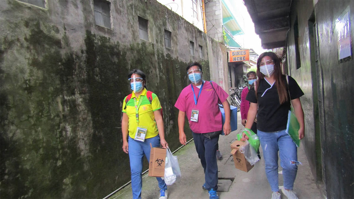 Street to street vaccination in the Philippines Masked health workers walk through narrow streets in the Philippines for a vaccination campaign.