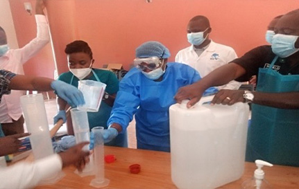 Masked workers attend a training on how to produce alcohol-based hand run.