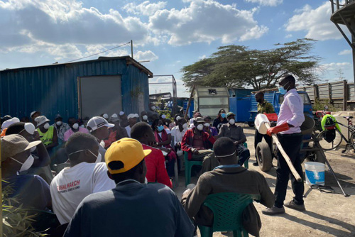 A group of workers listen to a trainer on proper hygiene
