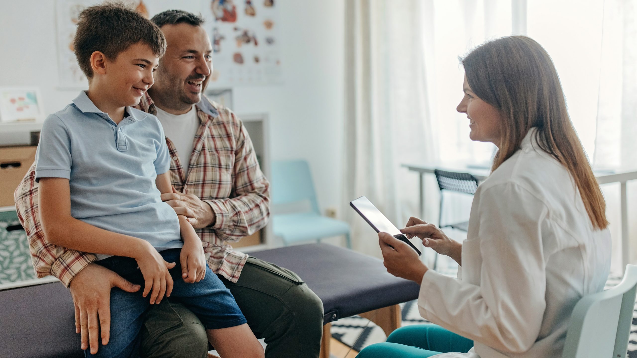 Health care talk with father and son Health care provider goes over chart with father and son in a medical setting.