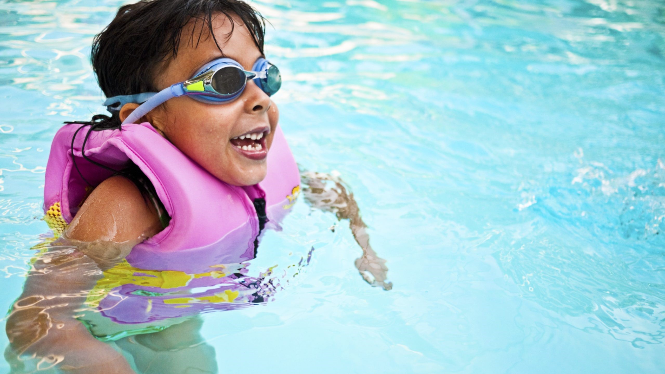 Boy in pool with lifejacket Young boy in pool wearing a lifejacket and goggles.