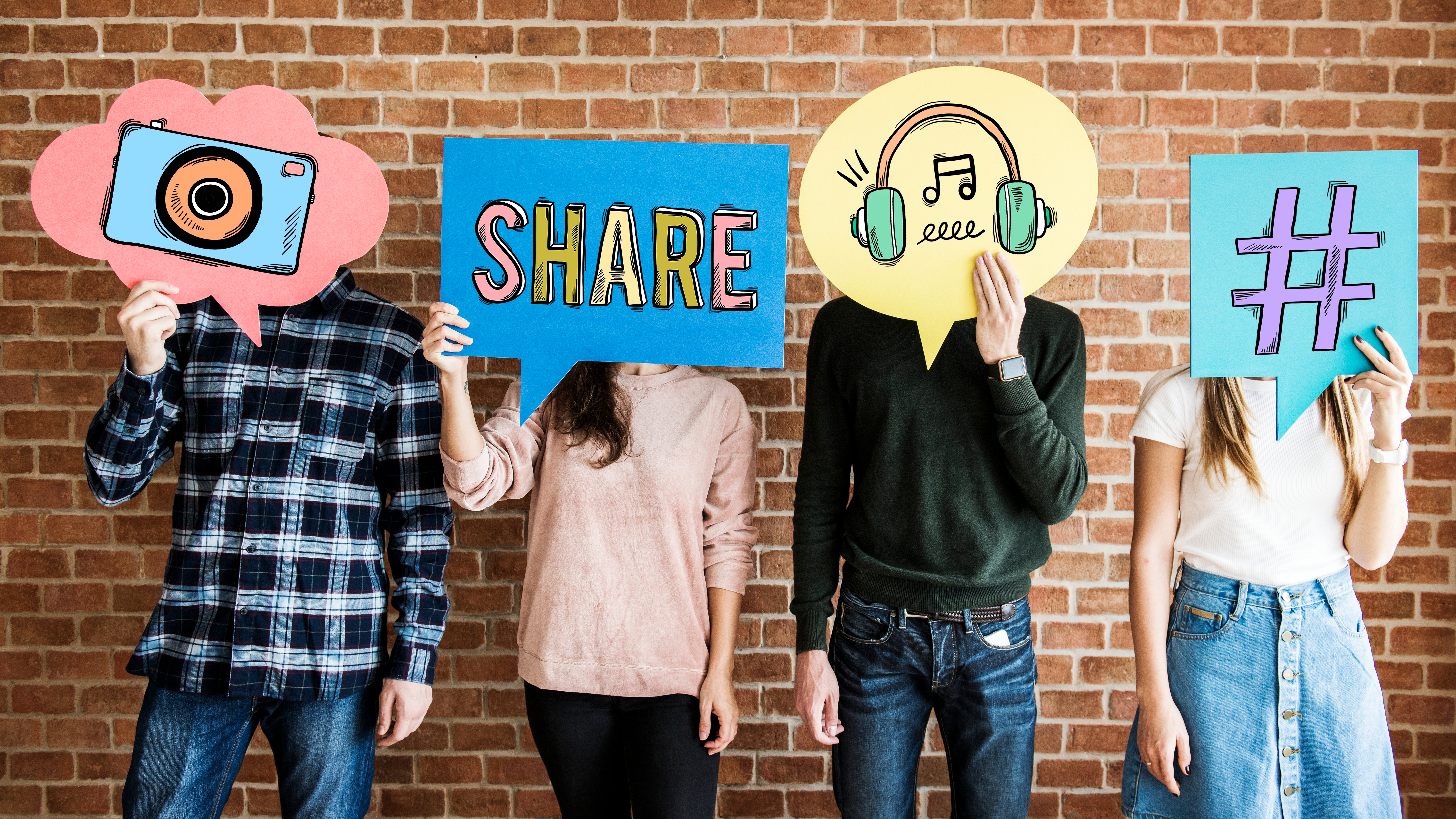 Students holding cardboard icons in front of their faces showing communication resources: share, hashtag, etc.